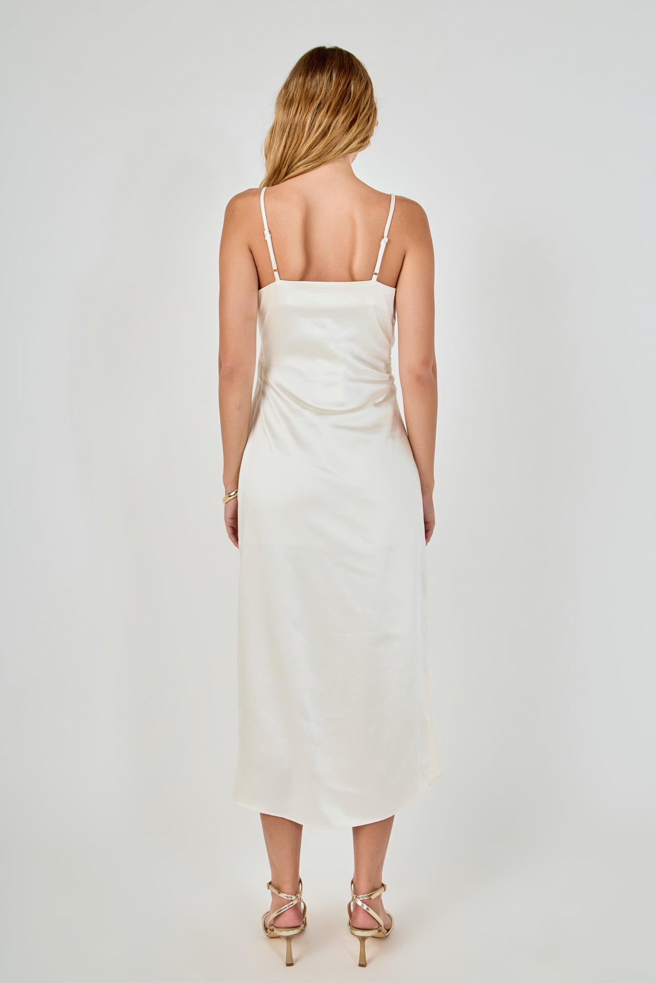 Straight-on rear view of a champagne satin wrap midi dress showing the slender adjustable shoulder straps and smooth back drape.