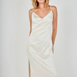 Face-forward posed view of a champagne satin wrap midi dress featuring a draped wrap neckline, subtle side ruching, and slender adjustable straps.