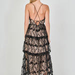 Back view of a black floral embroidered tiered midi dress featuring thin spaghetti straps, a straight back neckline, and a multi-tiered ruffled midi hem.