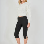 Side profile view of cream cropped cable-knit sweater displaying the long sleeve drape, wispy feather trim, and fitted waistline.