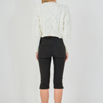Straight-on rear view of cream cropped cable-knit sweater showing continuous back cable detailing and wide ribbed hem.