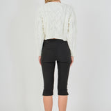 Straight-on rear view of cream cropped cable-knit sweater showing continuous back cable detailing and wide ribbed hem.