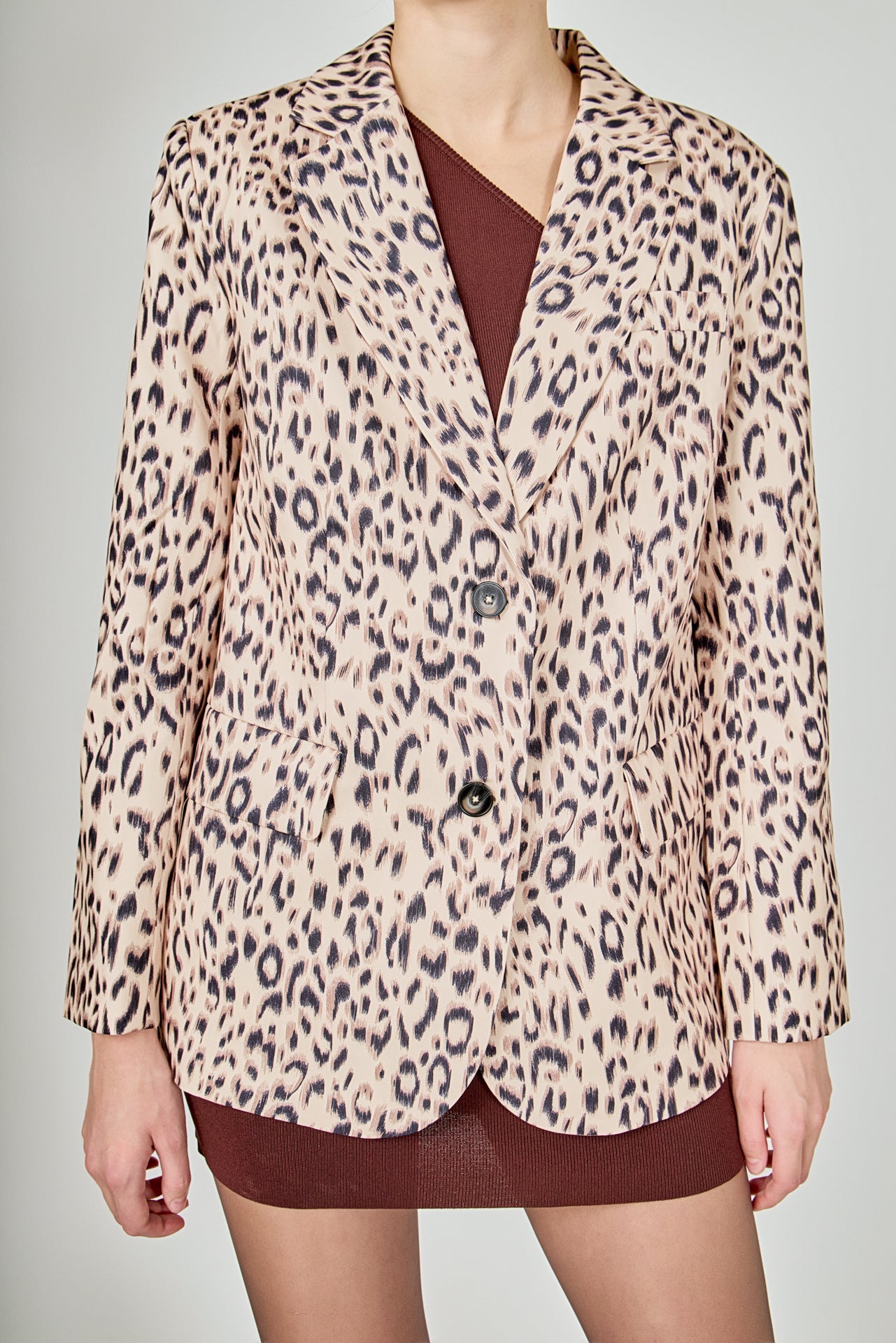 Beige multi leopard print woven oversized blazer featuring notched lapels, long sleeves with shoulder pads, front flap pockets, and a single-breasted button closure.
