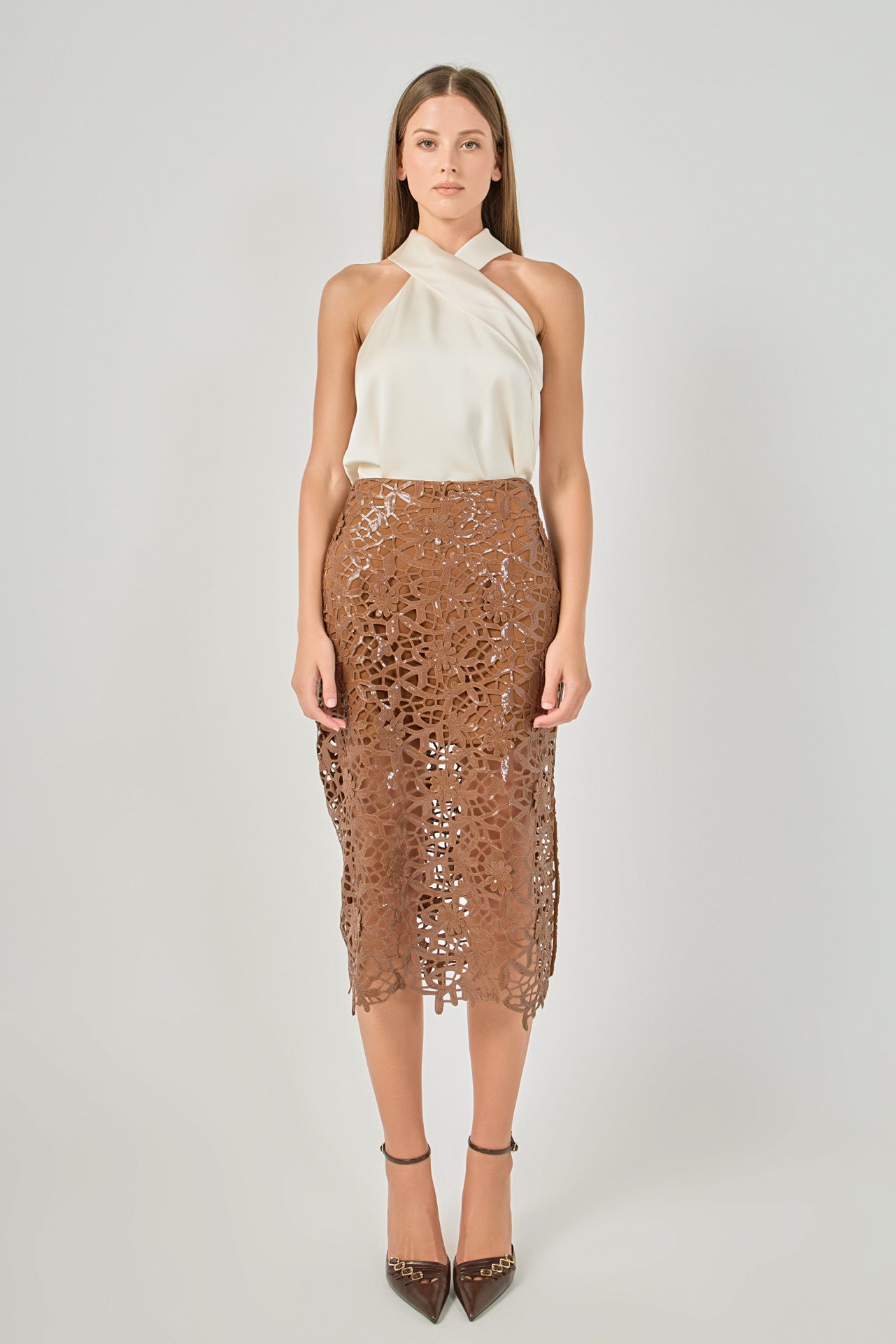 Full-length front view of an ivory satin top featuring a crossover halter neckline, styled with a brown laser-cut lace midi skirt.