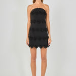 Black strapless mini dress featuring horizontal floral appliqué trim, scalloped neckline and hem, and a fitted silhouette.