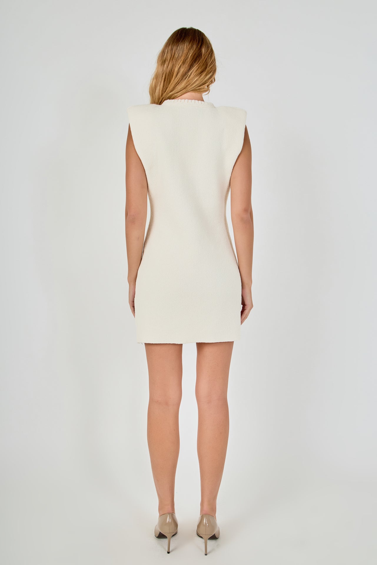 Straight-on rear view of a cream sleeveless knit mini dress showing the clean back profile and wide cap shoulder design.