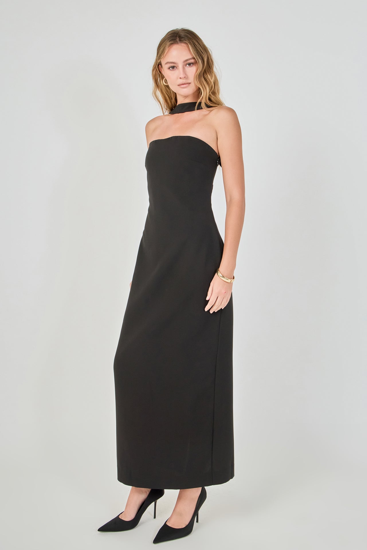Side view of a black strapless column maxi dress featuring a slim fitted silhouette and matching neckband detail.