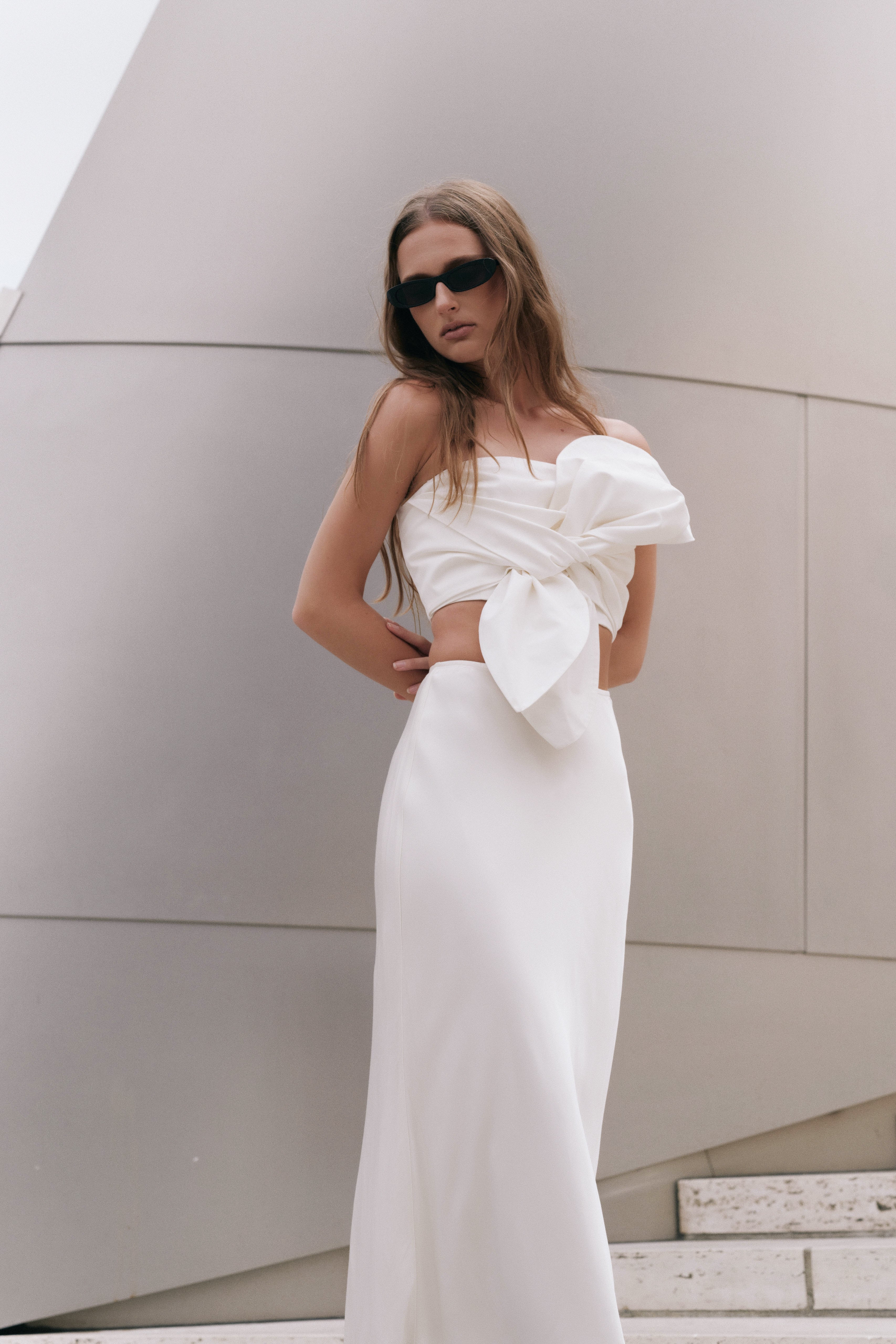 Posed three-quarter view of an ivory satin slip maxi skirt displaying the flat front waist and soft satin finish.